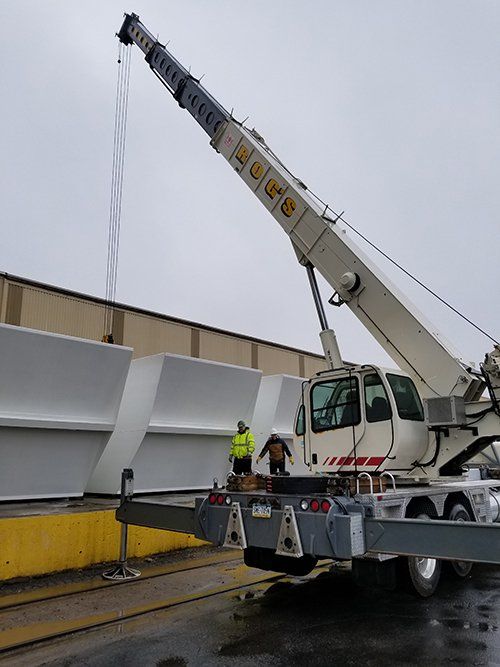 A large crane is being used to lift a large piece of metal.
