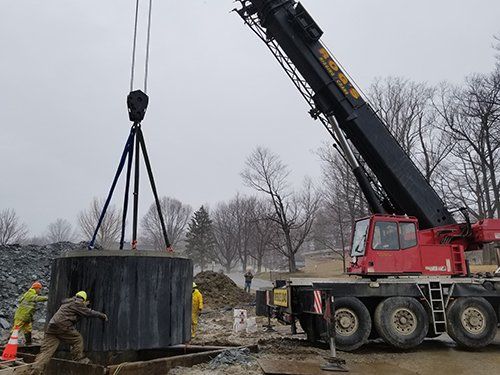 A red crane is lifting a large black object