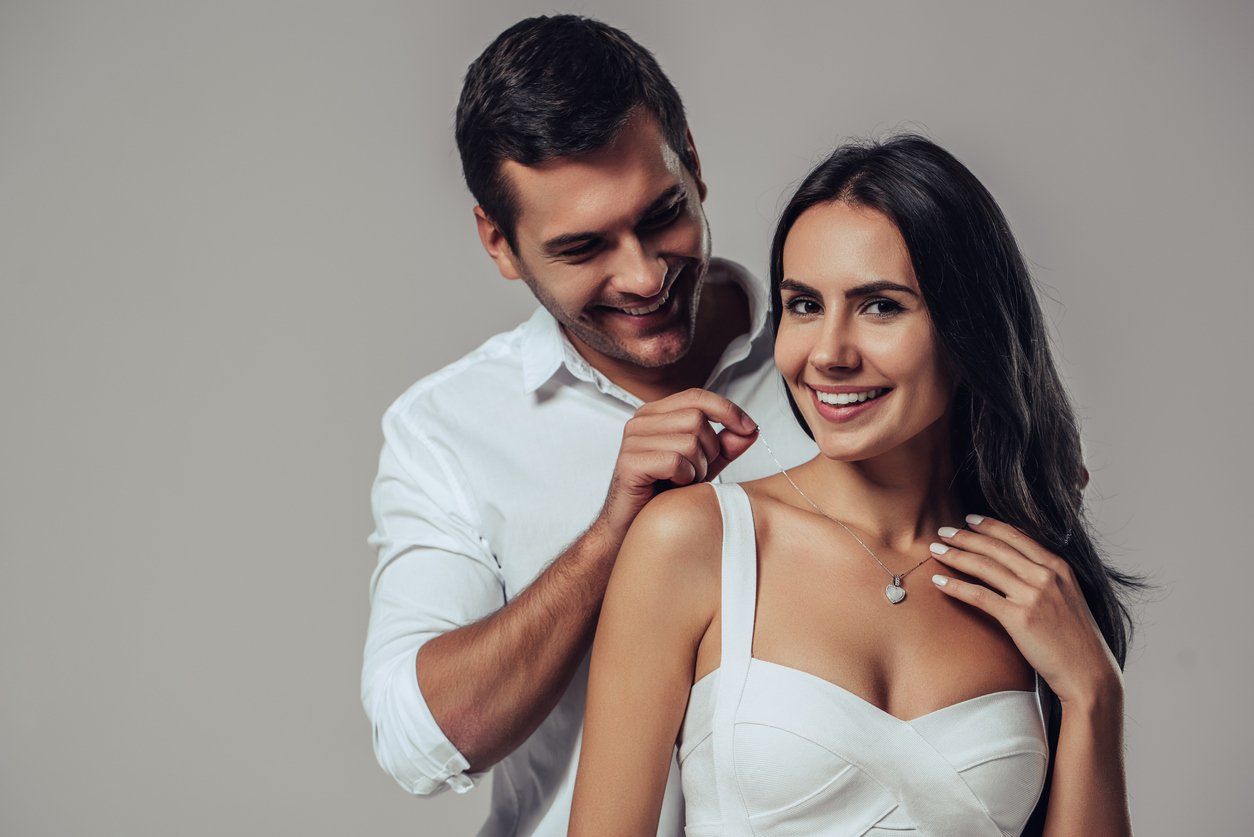 man gifting woman a heart shaped necklace