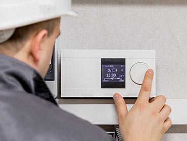Technician adjusting thermostat - HVAC Contractor in Kernersville, NC Technician adjusting thermostat - HVAC Contractor in Kernersville, NC