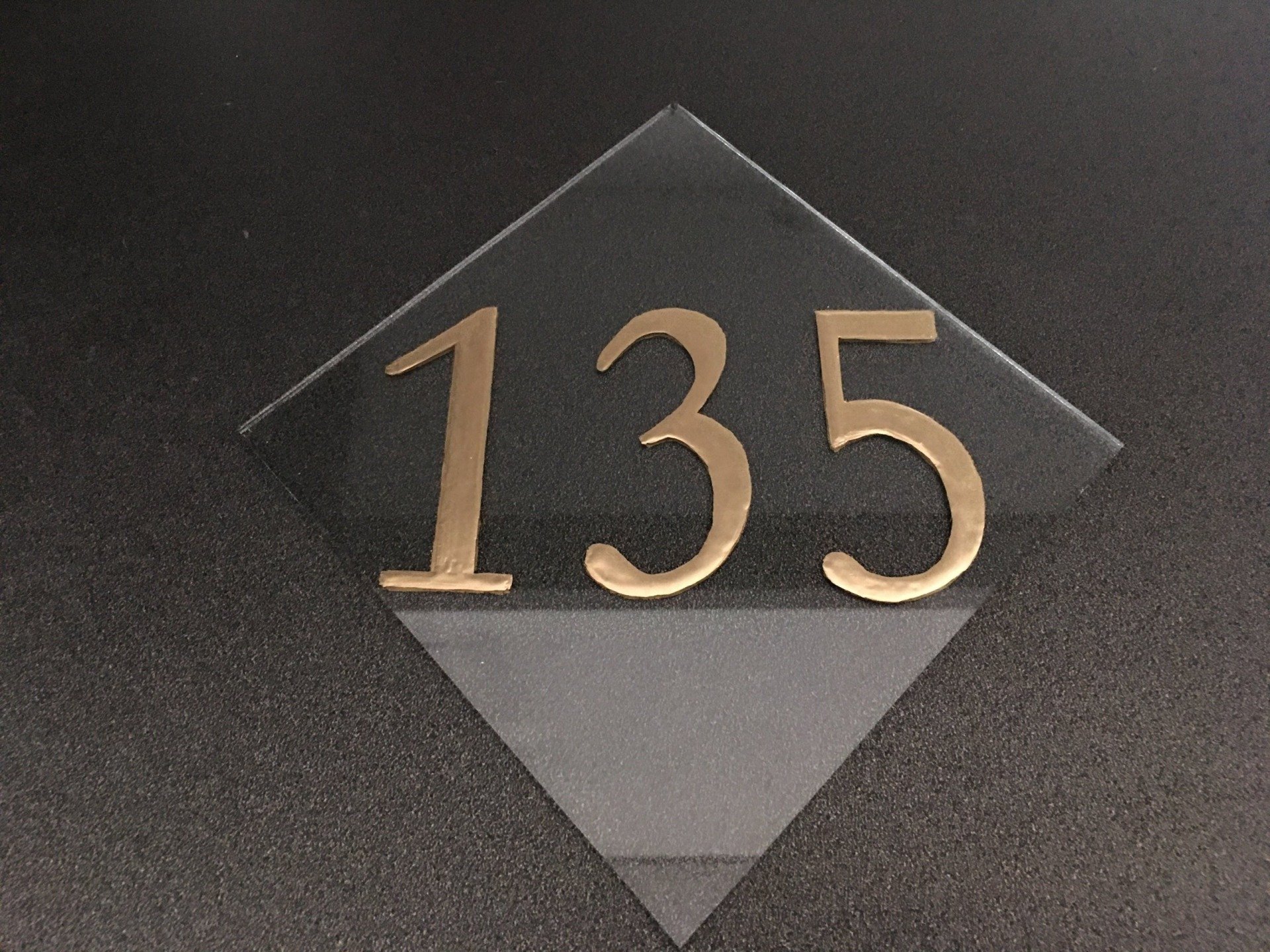 Gold “135” numbers on a dark diamond-shaped plaque.