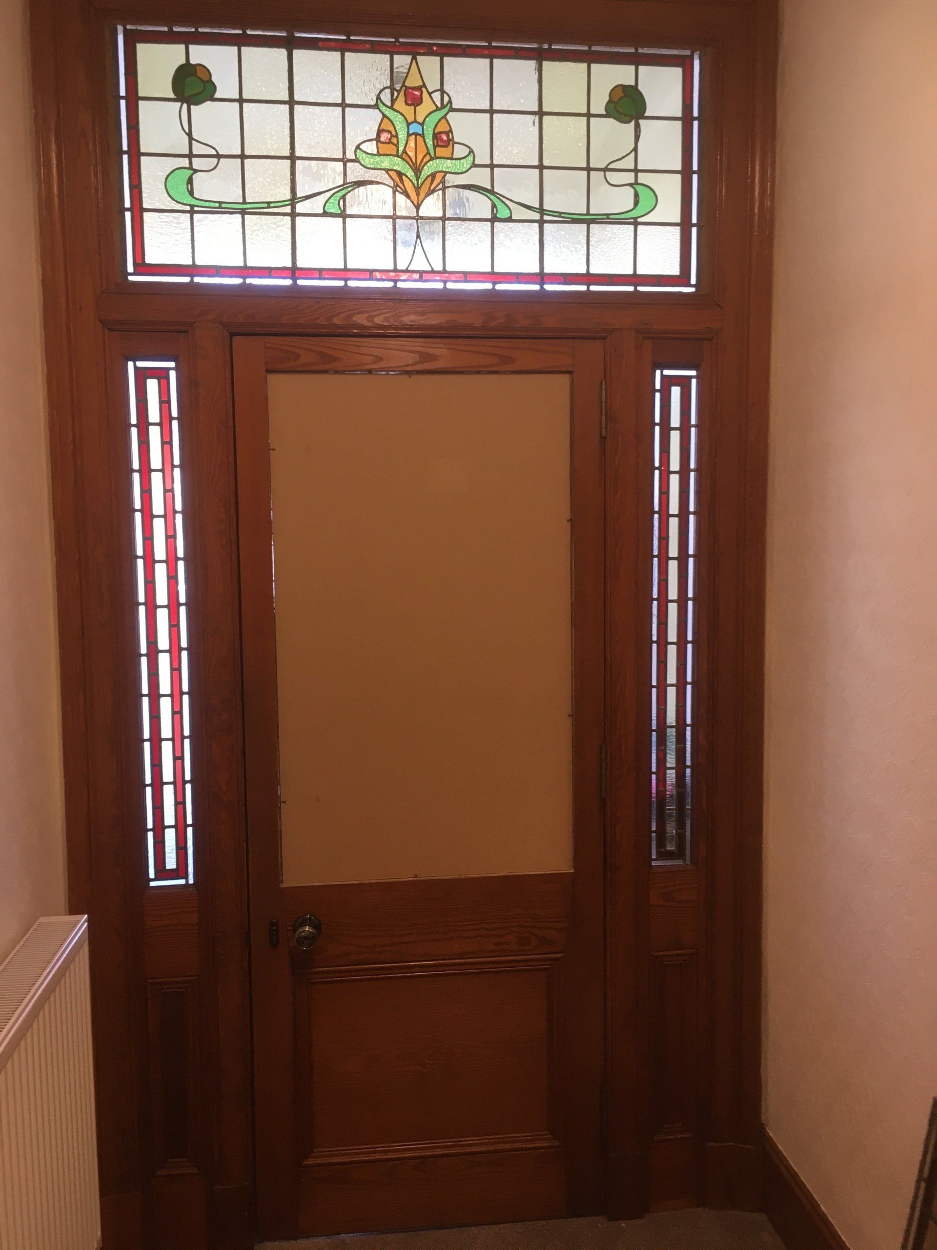 Wooden front door with stained glass panels and sidelights in a hallway