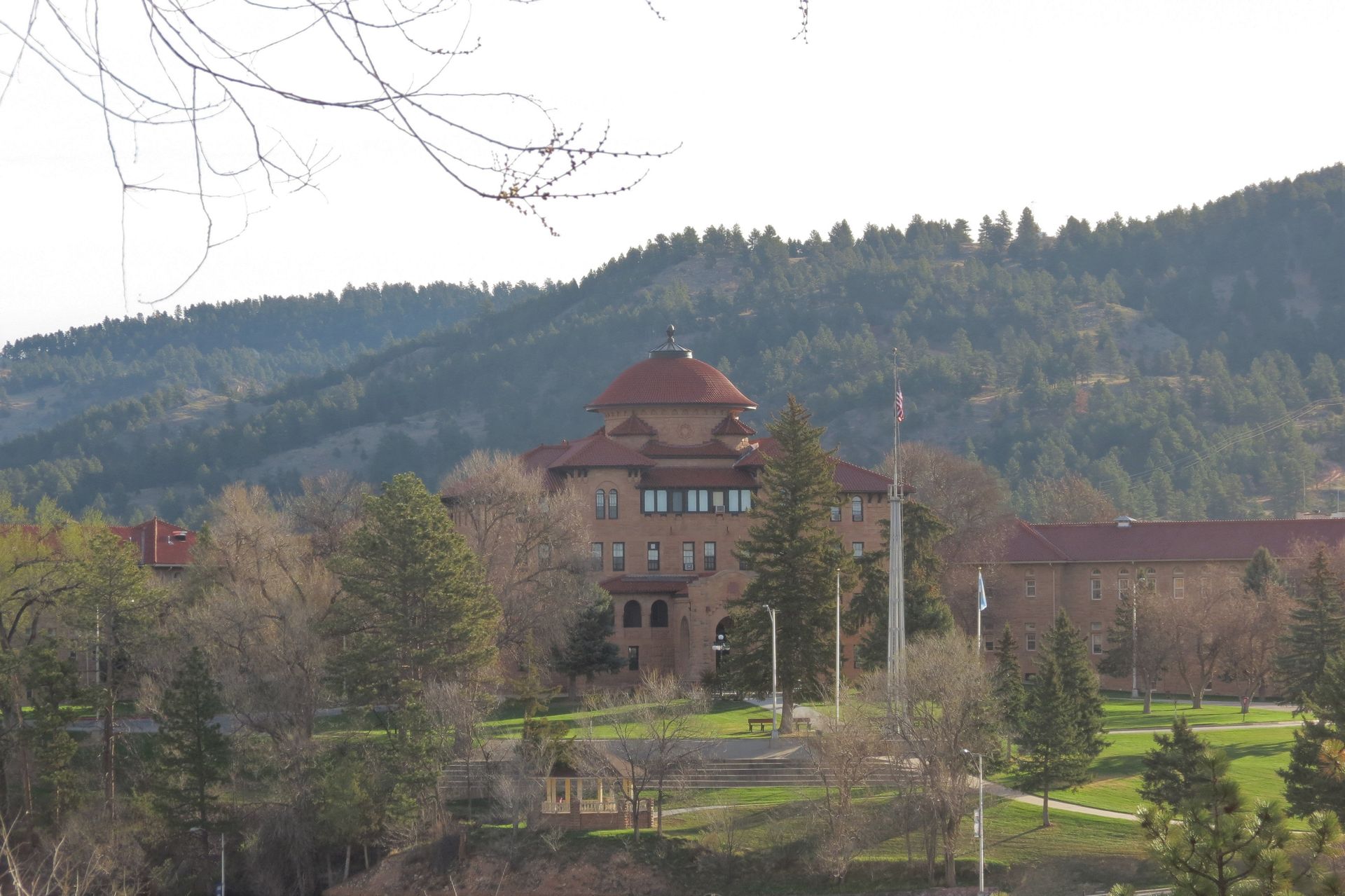 A large building sits on top of a hill surrounded by trees.