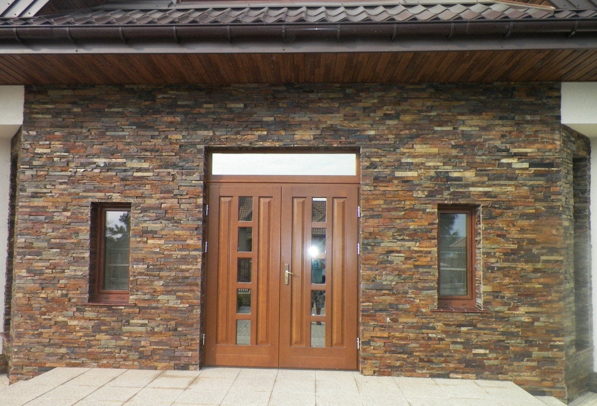 Brown brick facade with wooden double doors and windows.