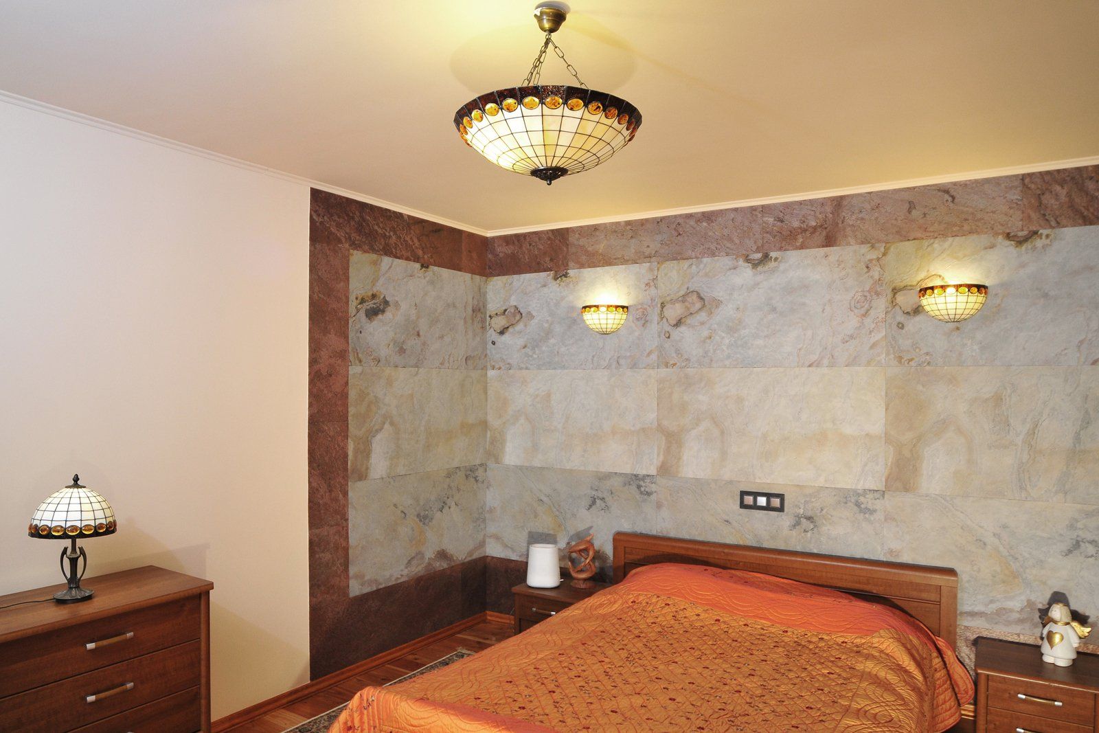 Bedroom with a bed, dresser, lamps, and decorative stone wall.