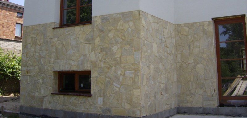 Exterior of a building with stone siding on the lower portion of the wall, windows, and a doorway.