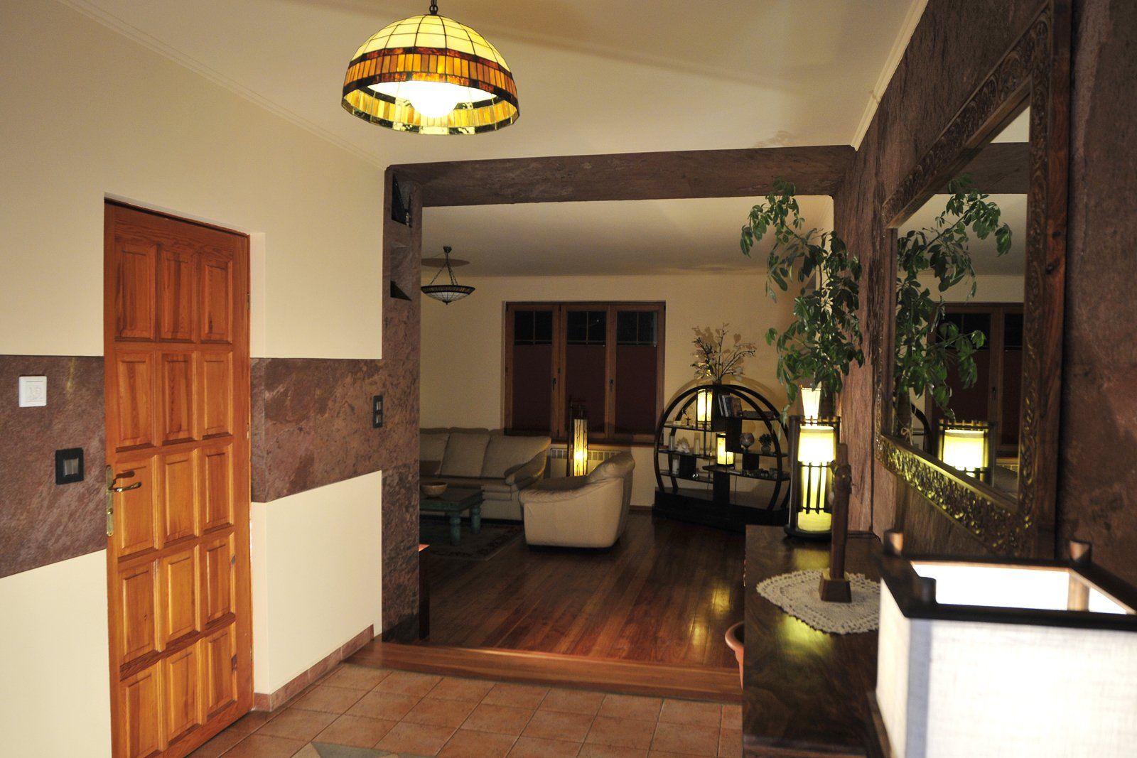 Entryway with wooden door, stone walls, and view into living room with wood floors and furniture.