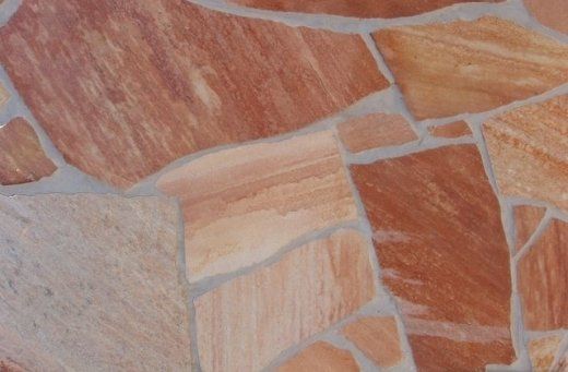 Stone tile mosaic with shades of red, orange, and tan, with gray grout lines.