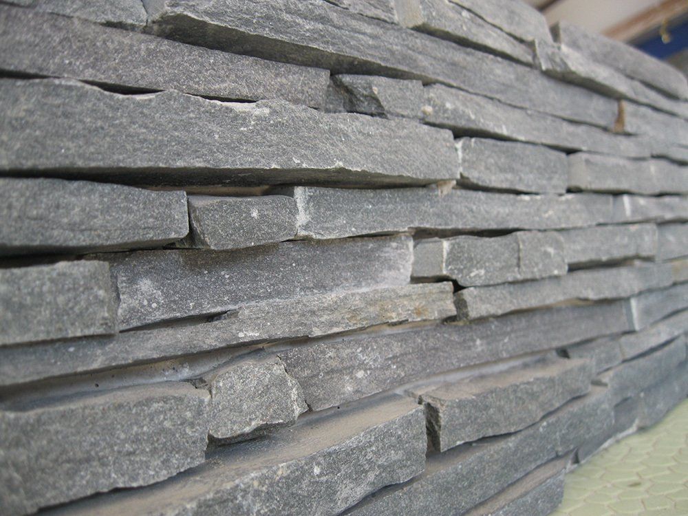 Close-up of a stacked stone wall with gray rectangular pieces and rough texture.