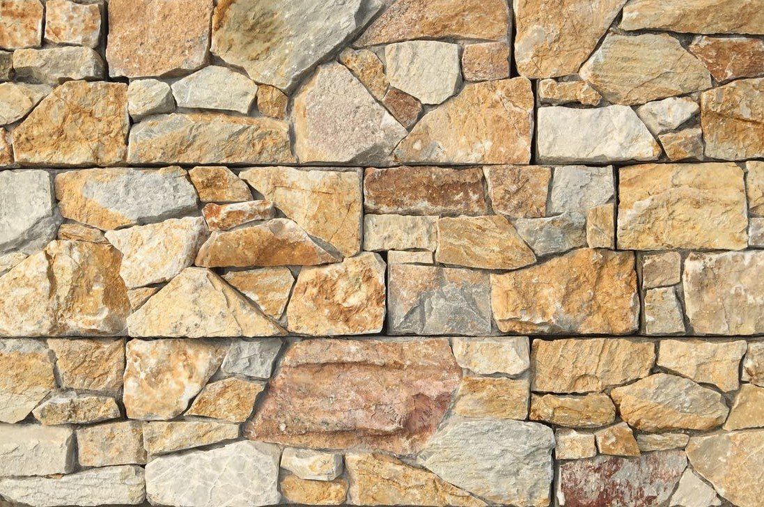 Tan and beige stone wall with varied shapes and sizes, mortared together.