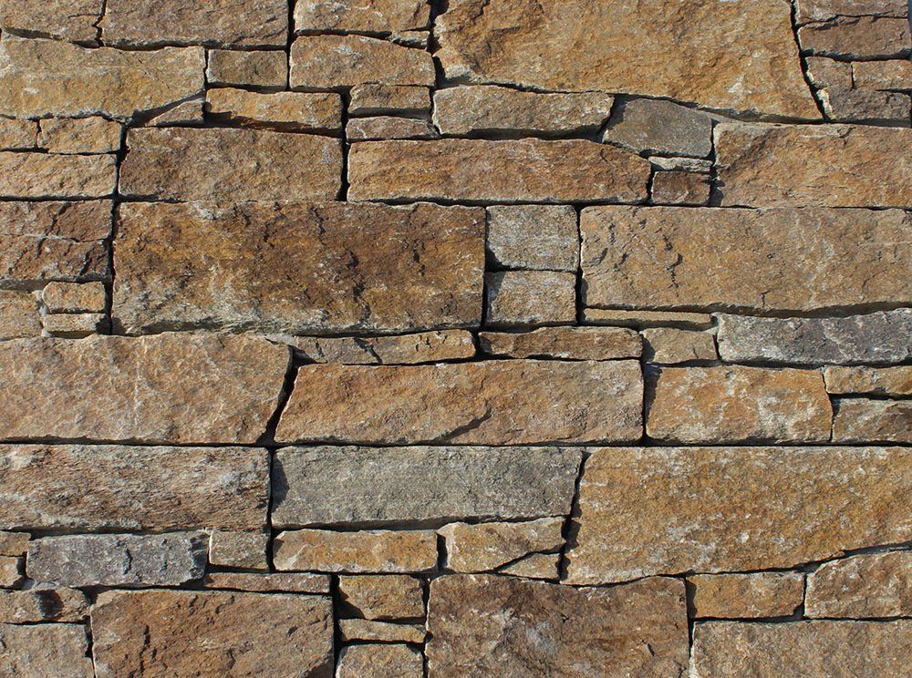 Stone wall with various rectangular and irregular brown and tan stones.