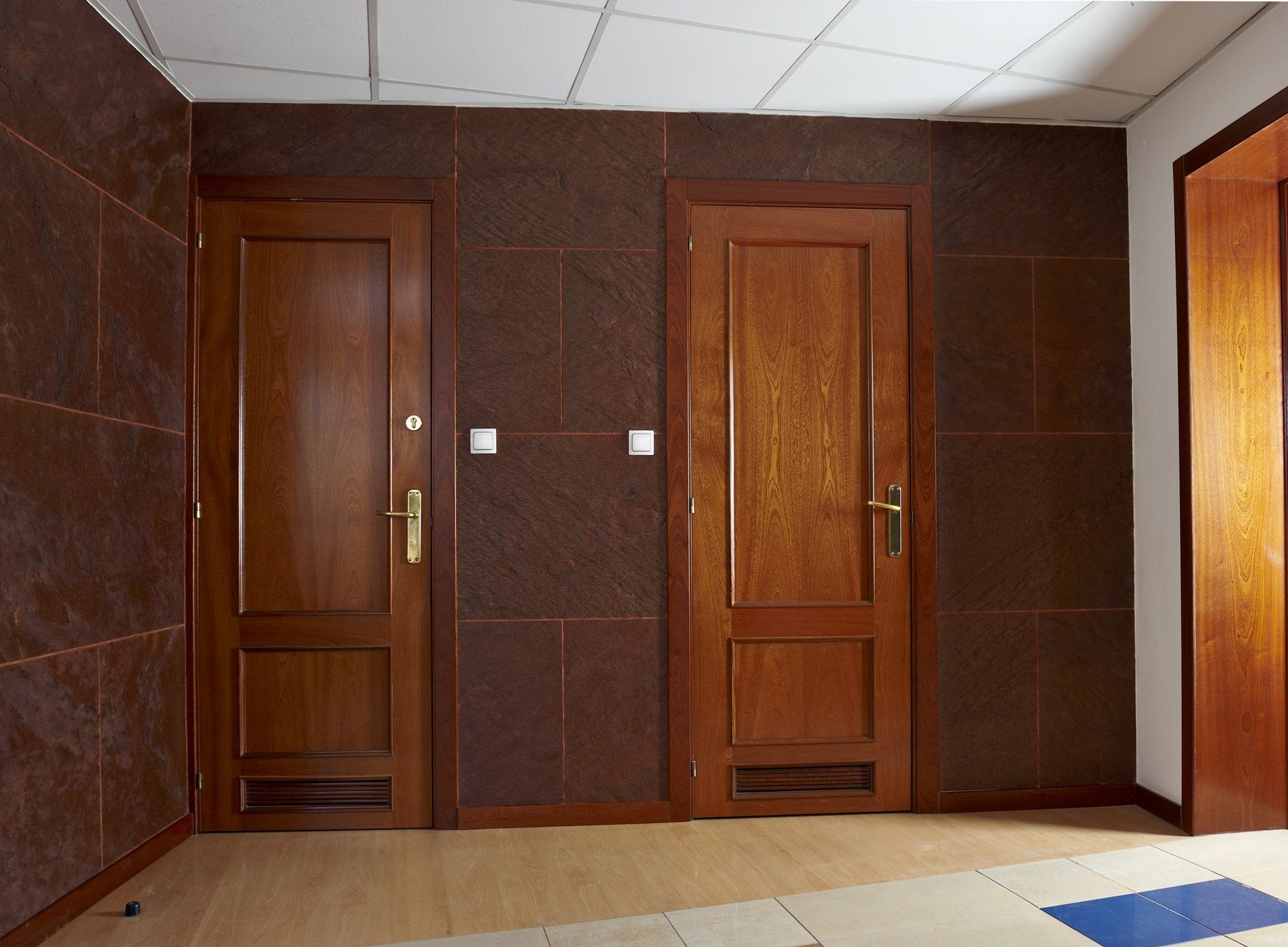 Two closed brown wooden doors in a room with brown textured walls and a white ceiling.