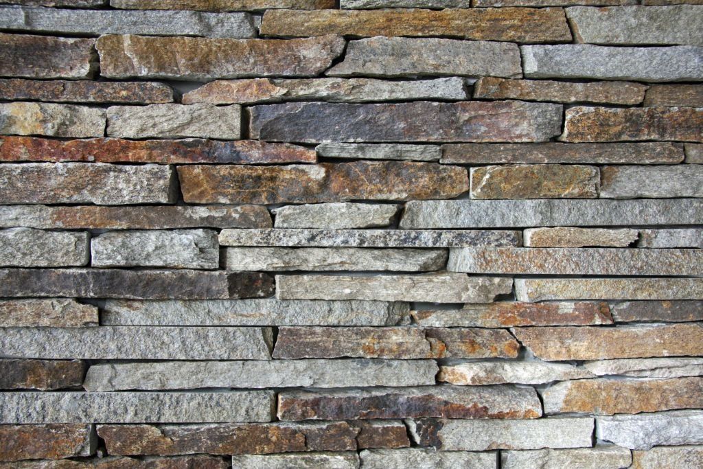 Stone wall with varying shades of brown, gray, and gold; textured and horizontal lines.
