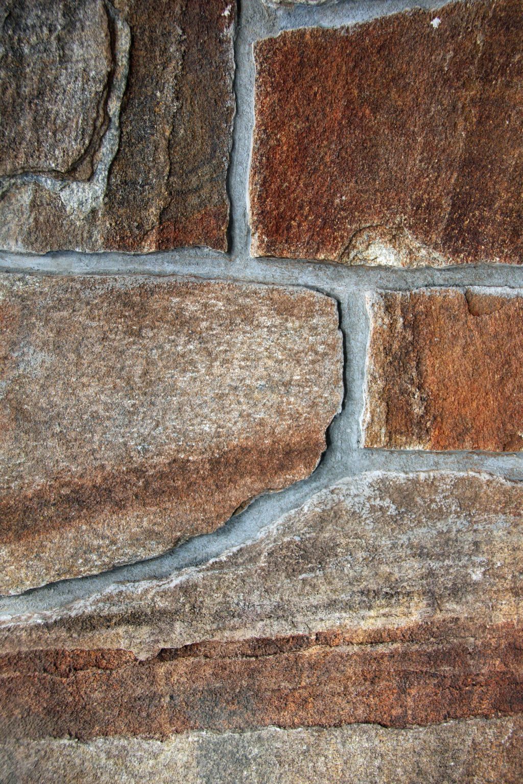 Close-up of a stone wall. Brown and gray rectangular stones with gray mortar.