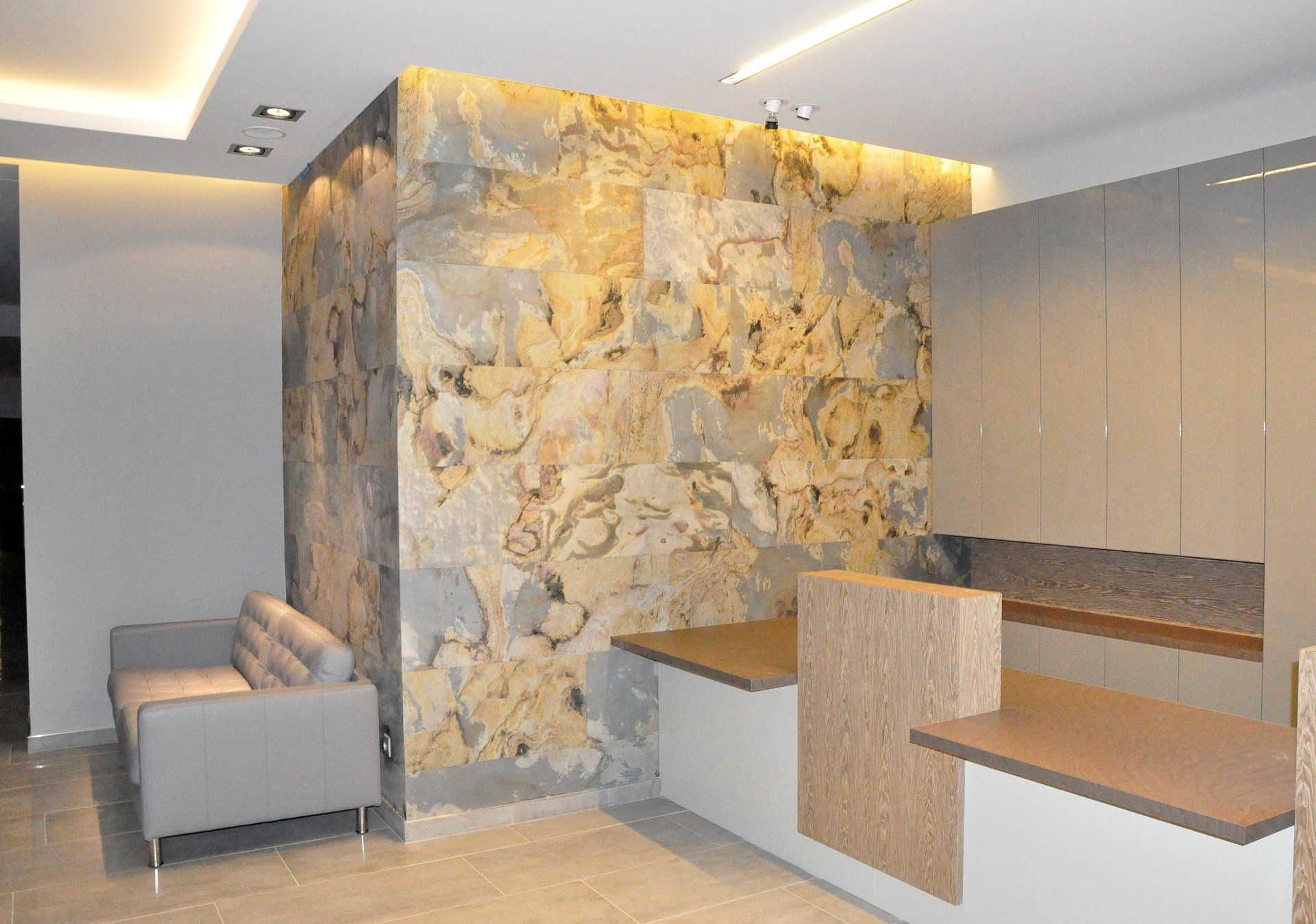 Reception area with stone wall, light gray sofa, and wooden desk.