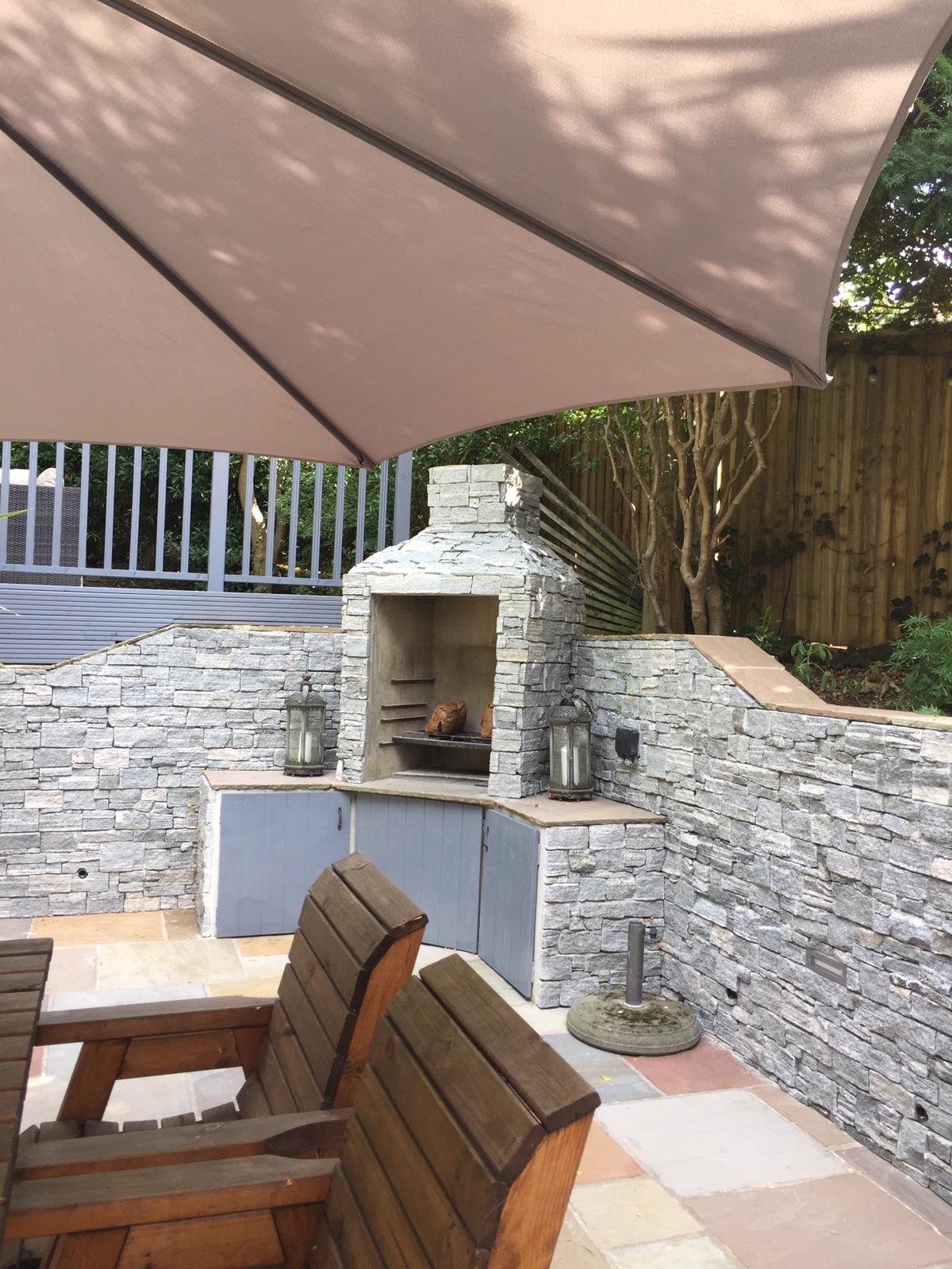 Outdoor stone fireplace and seating area with a large umbrella.