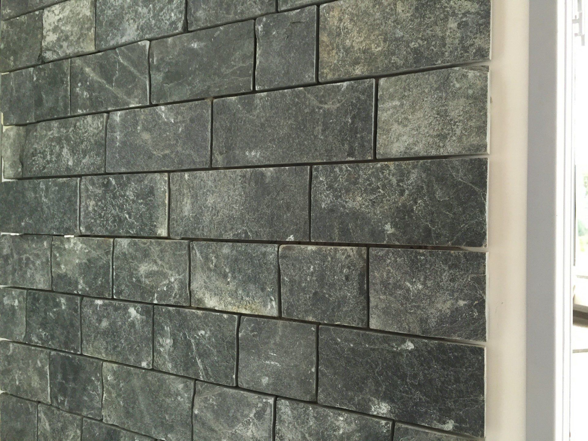 Dark gray brick wall with textured surface and visible grout lines.