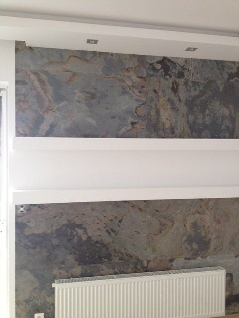 Wall with a textured stone pattern in blues and browns, separated by white sections. A radiator sits below.