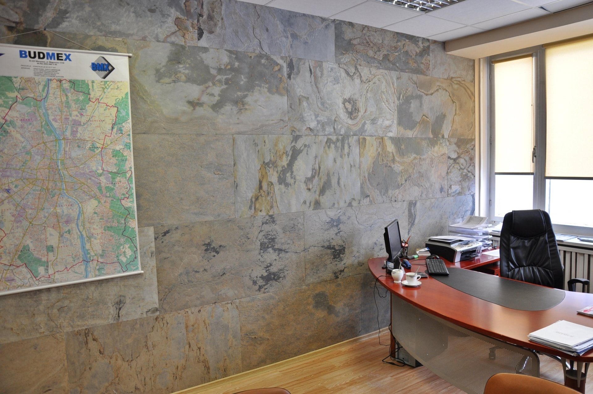 Office interior with stone wall, desk, map, and window.