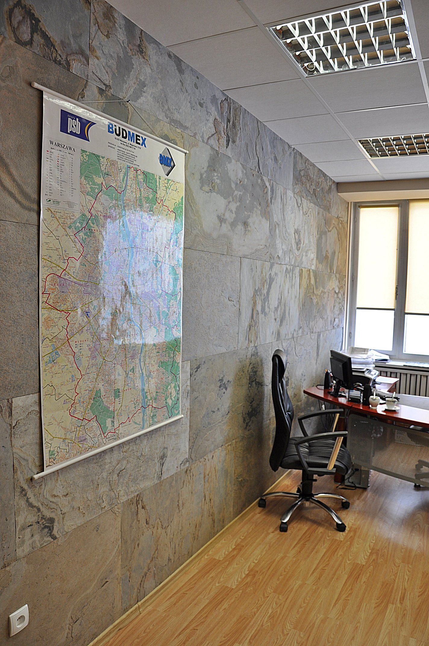 Office interior with map on wall, desk, chair, and window. Walls have a textured, aged appearance.