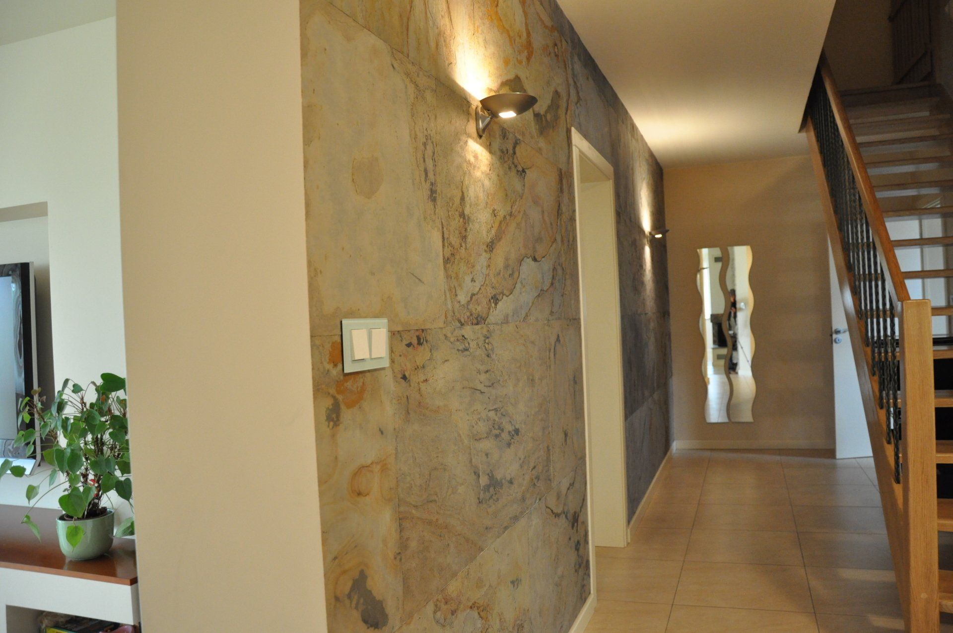 Hallway with stone wall, recessed lighting, neutral colors, and a wooden staircase.