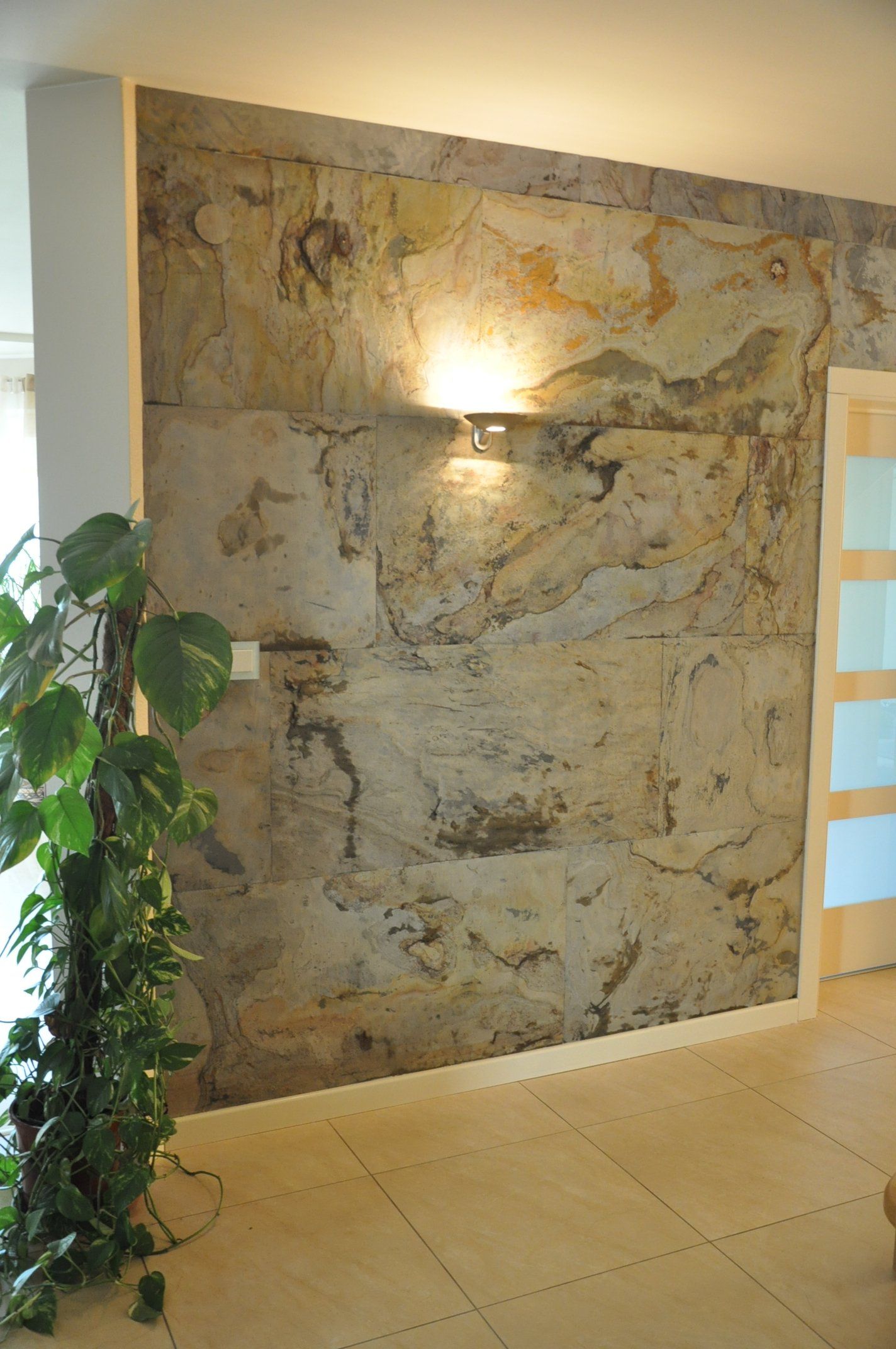 Textured stone wall with soft lighting and a climbing plant next to a door.
