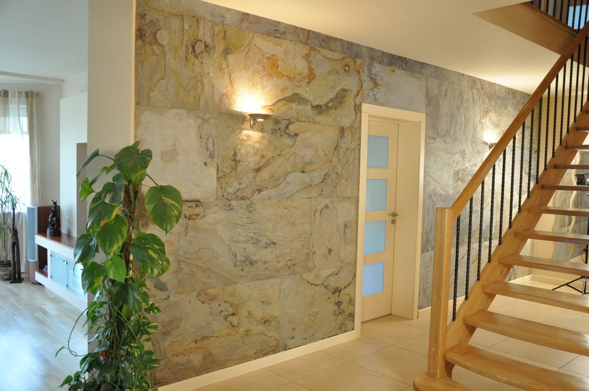 Hallway with stone-like accent wall, wooden stairs, and a houseplant.