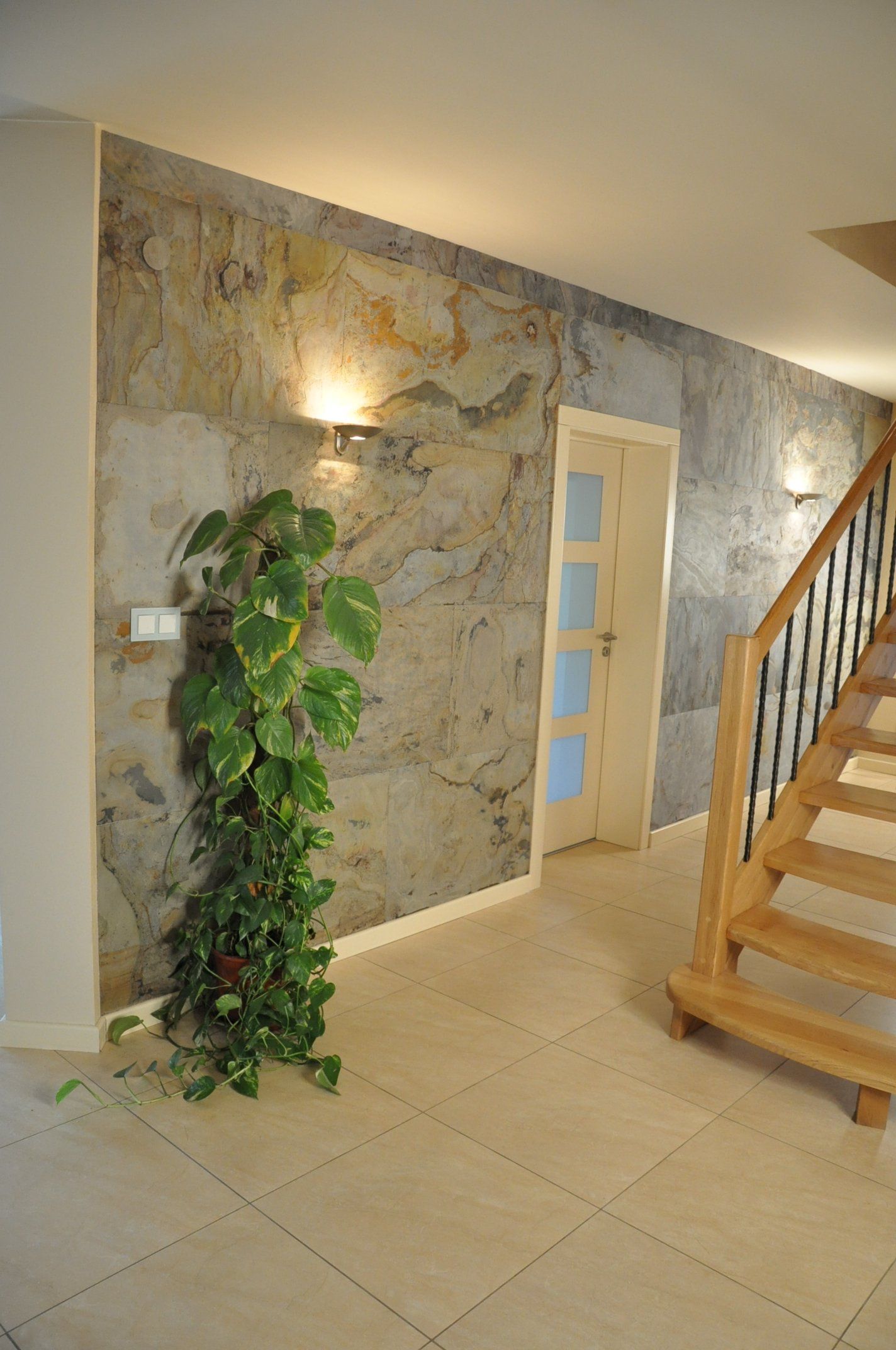 Hallway with textured accent wall, staircase, potted plant, and a closed door.