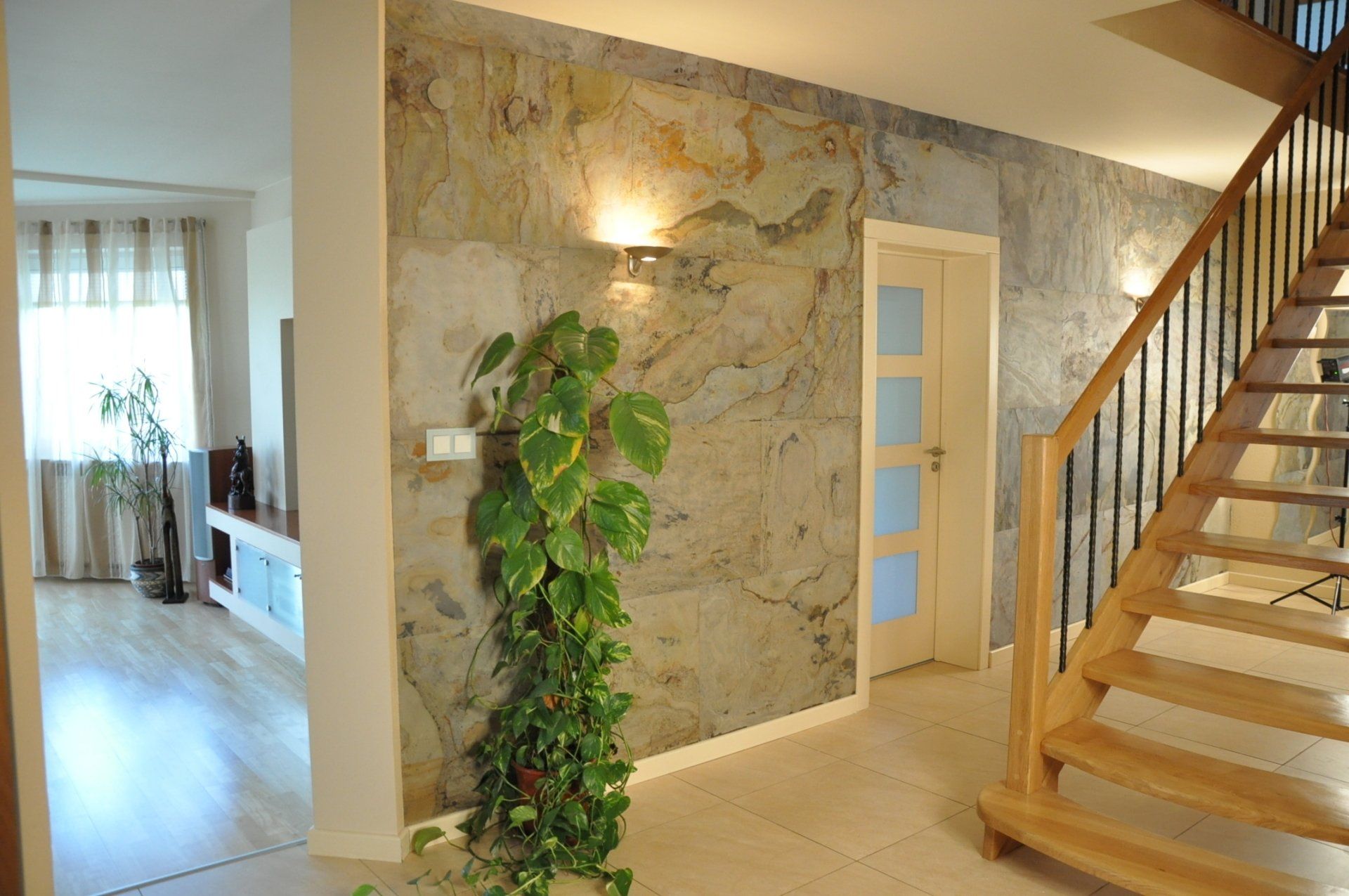 Hallway with stone accent wall, staircase, potted plant, and door.