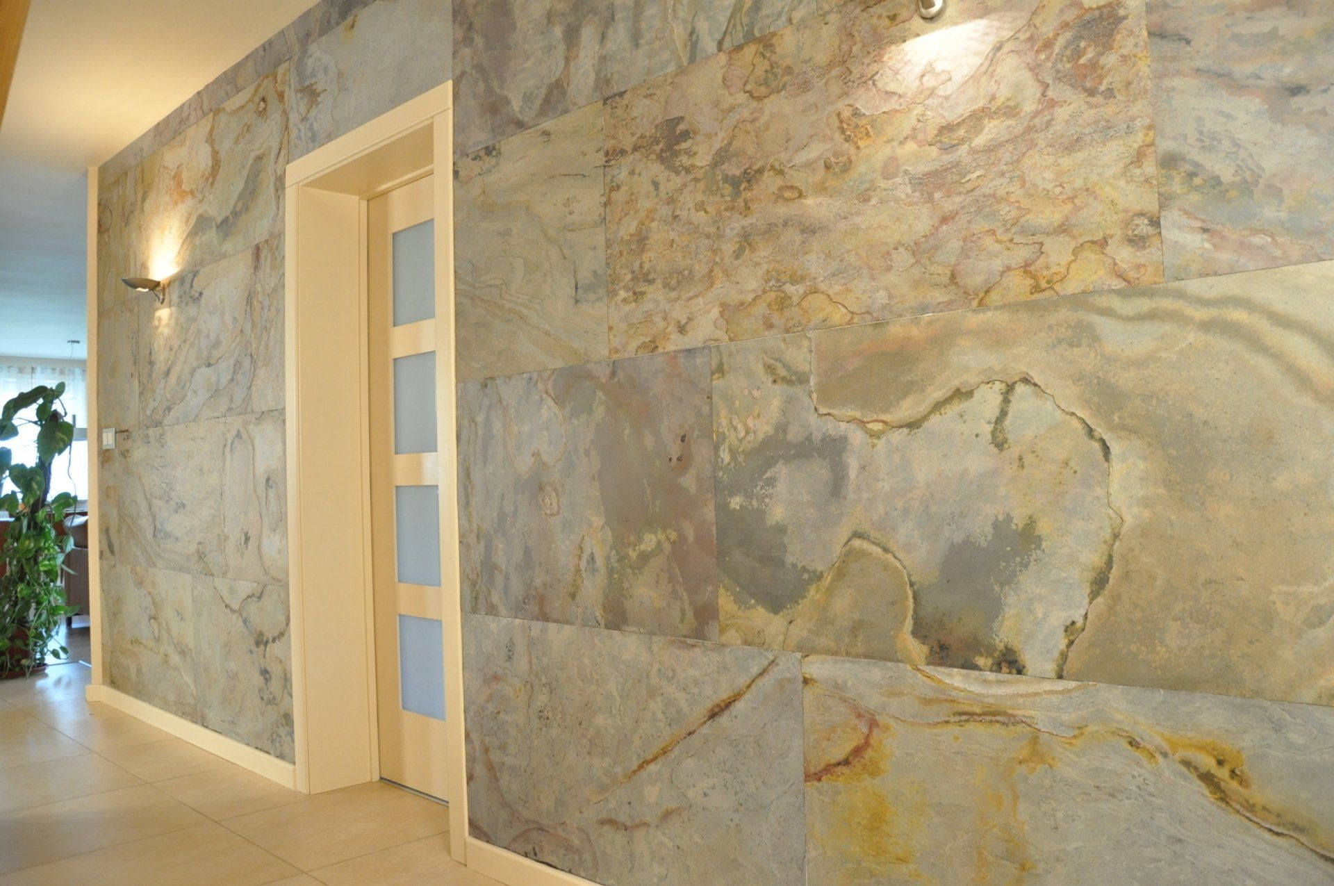Entryway with slate-tiled accent wall, cream door, recessed lighting, and hallway.