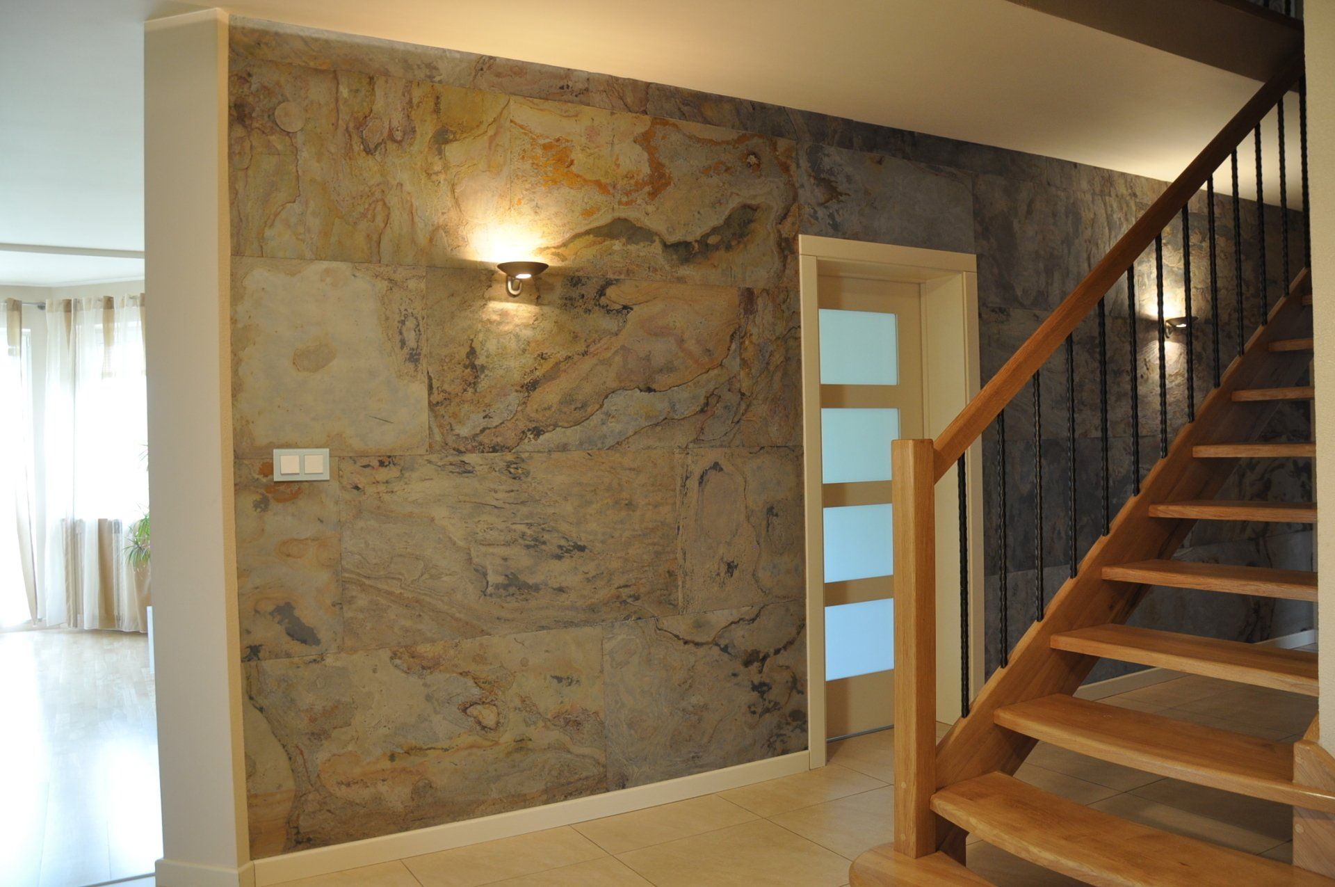 Interior view of a hallway with a stone accent wall, wooden staircase, and a doorway.