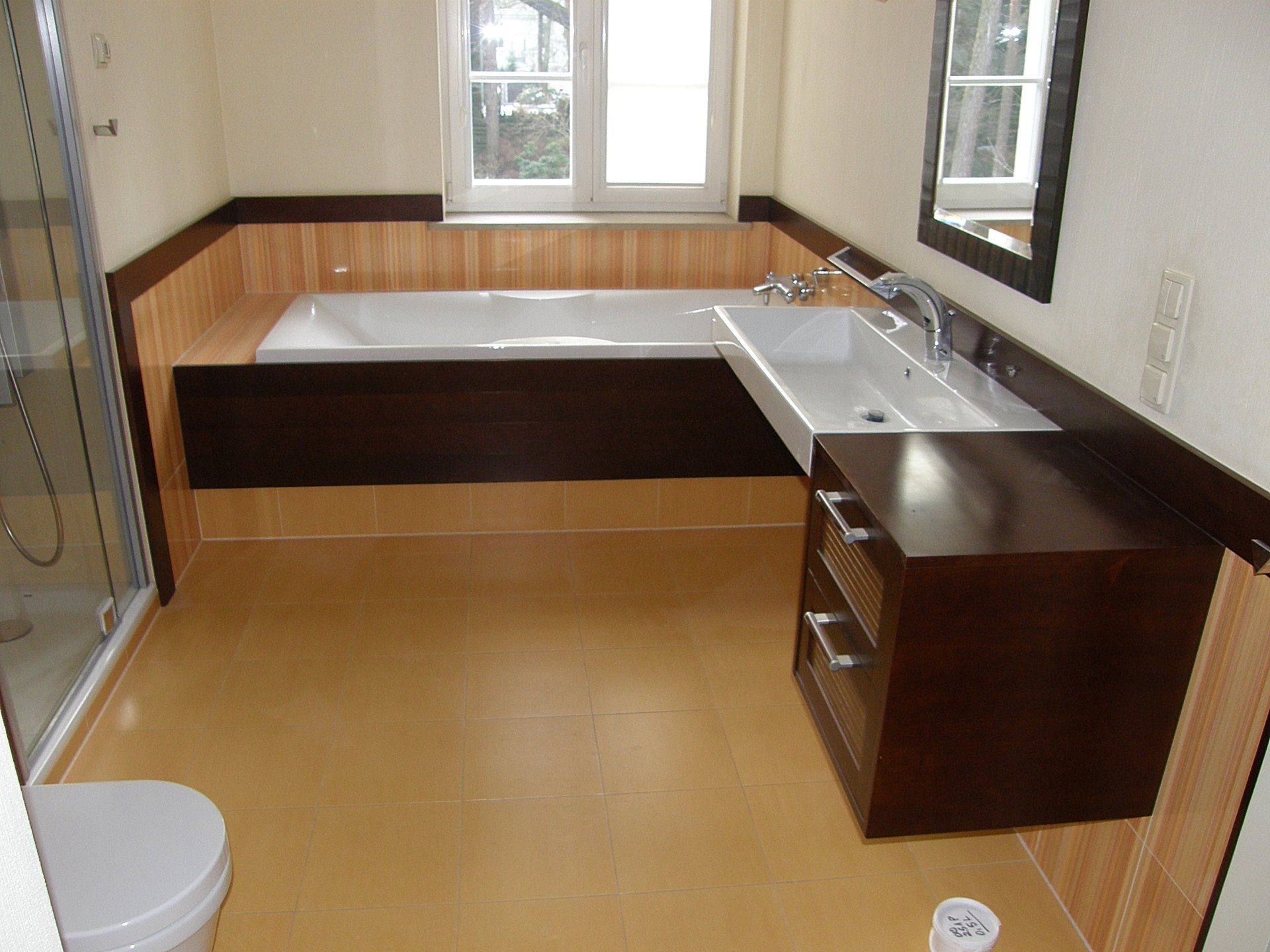 Bathroom with bathtub, sink, and toilet; dark brown cabinetry, light brown walls, and yellow floor.