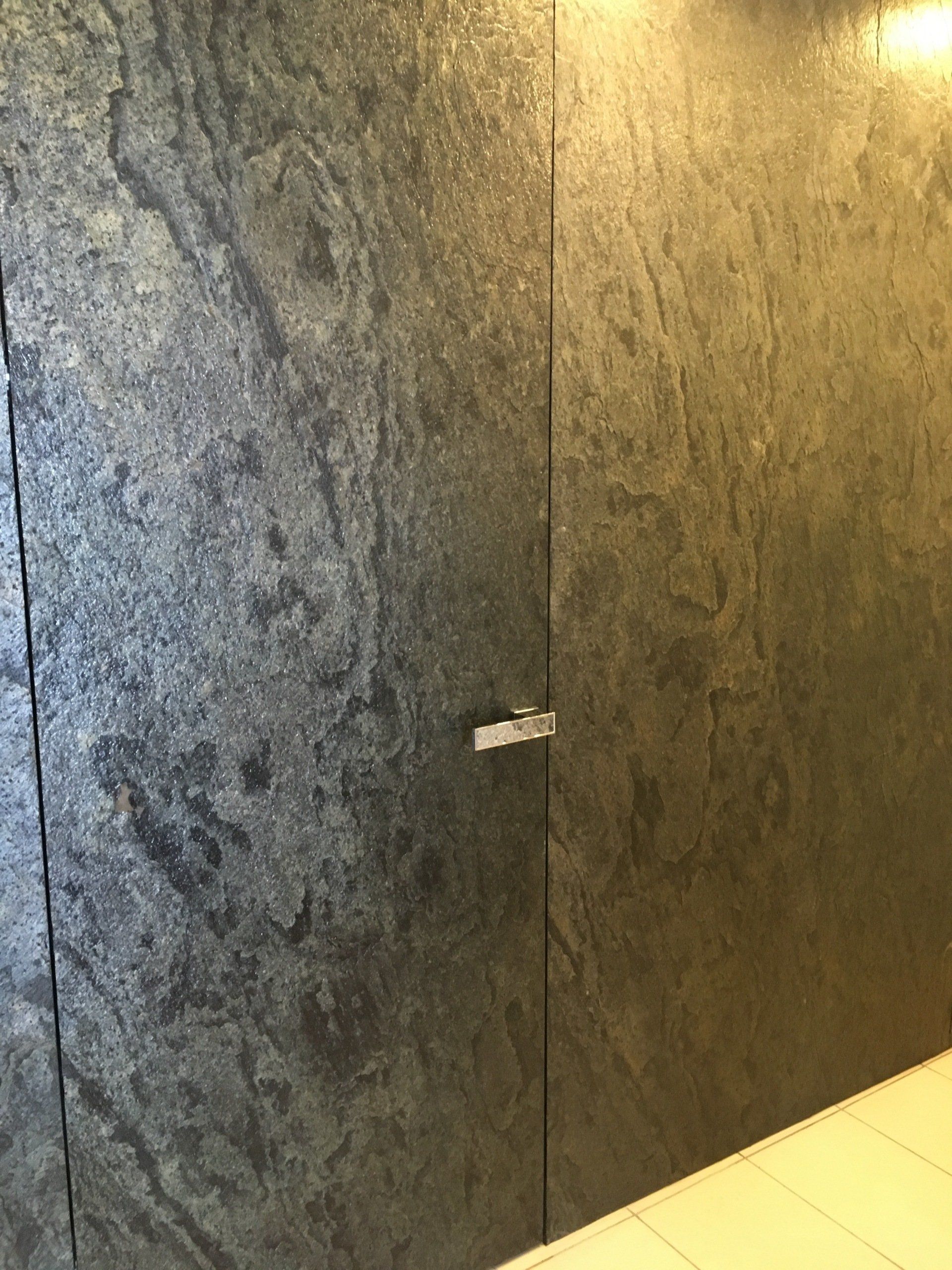 Dark gray textured stone wall with a small silver handle.