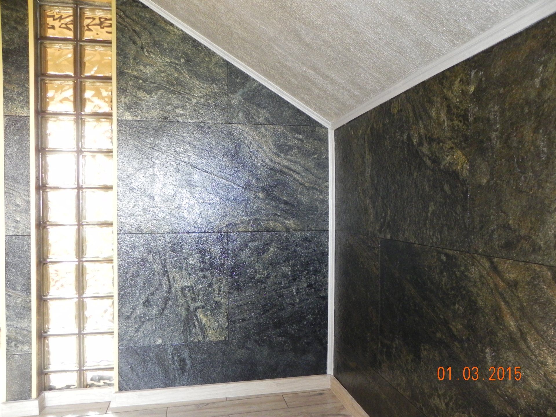 Dark green and gold stone-tiled walls with a glass block window and white trim.