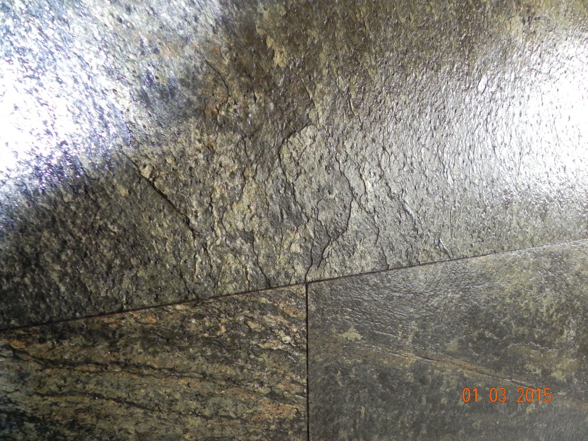 Close-up of slate tiles in shades of gray, black, and gold, with textured, uneven surfaces.