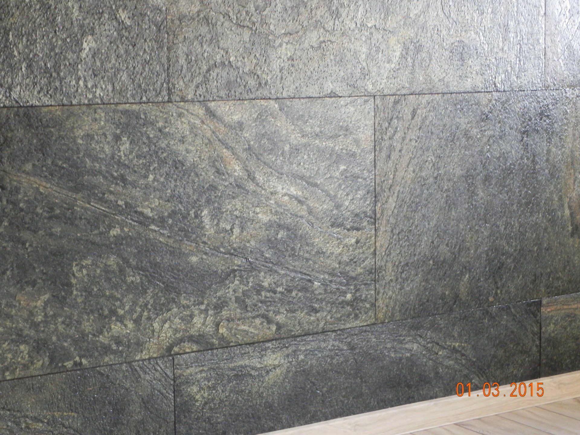 Textured dark stone wall tiles with varying gray and tan hues.