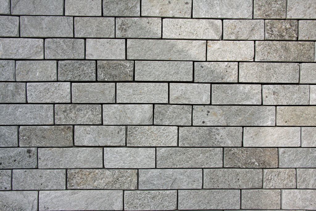 Gray brick wall with horizontal rectangular stones and visible mortar.