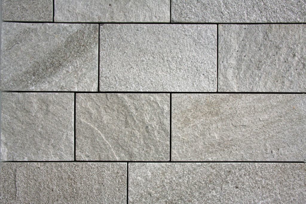 Gray rectangular stone wall with dark grout lines.