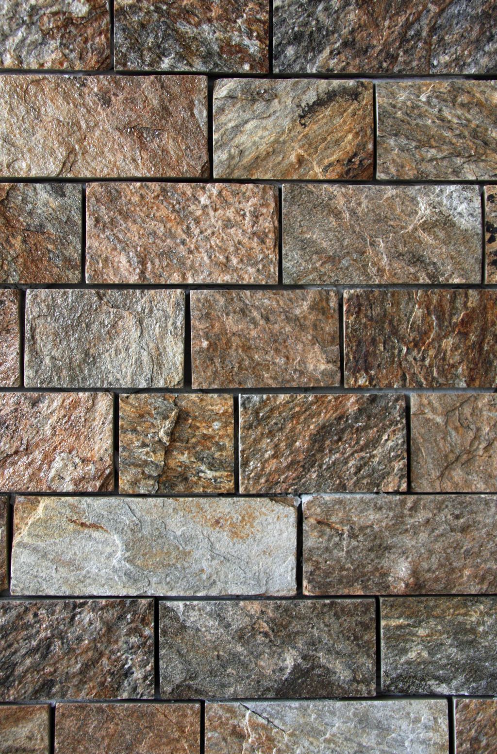 Brick wall with textured brown, tan, and gray rectangular stones arranged in a staggered pattern.