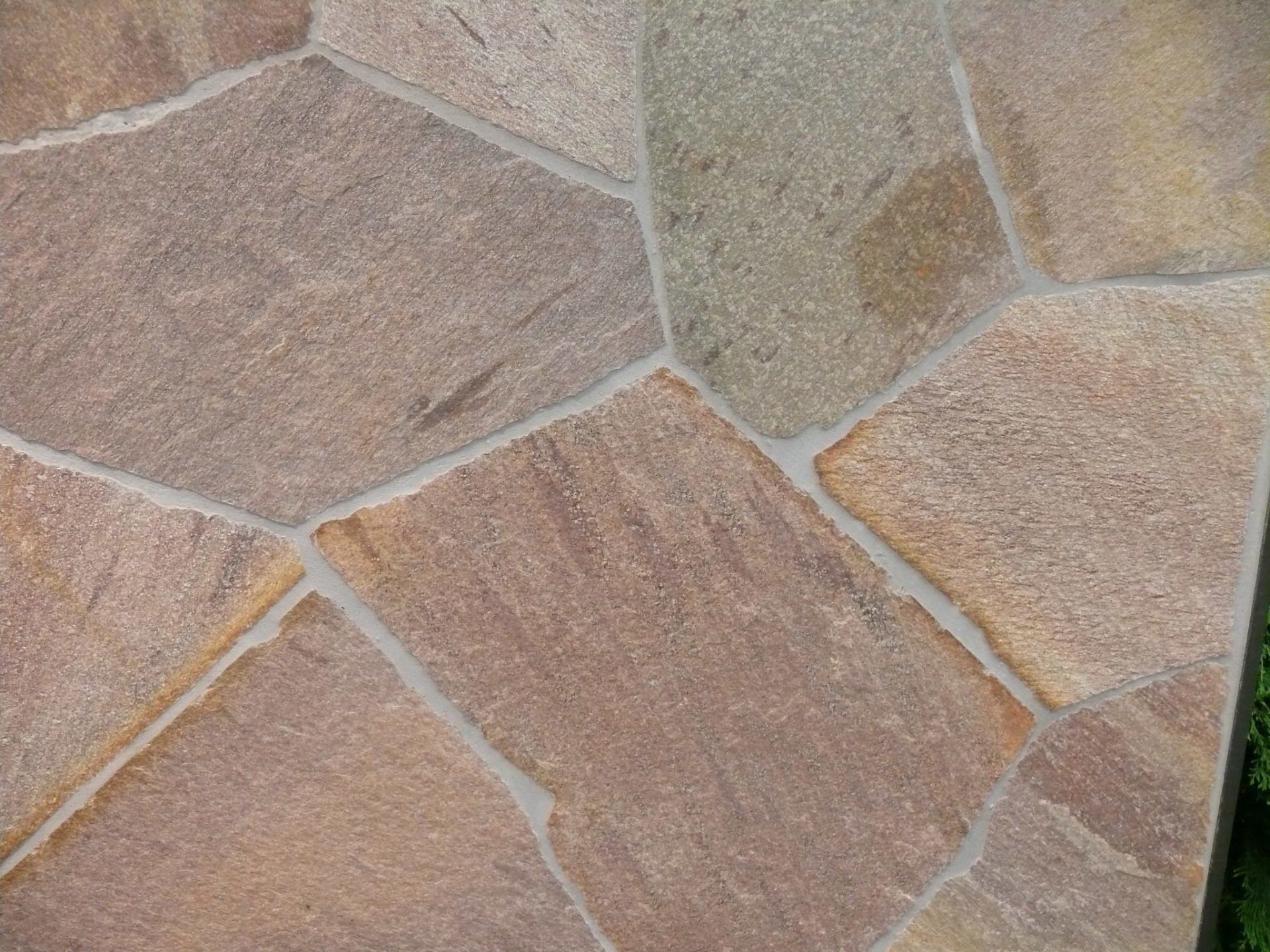 Flagstone patio with irregular tan and brown stones, light gray grout.