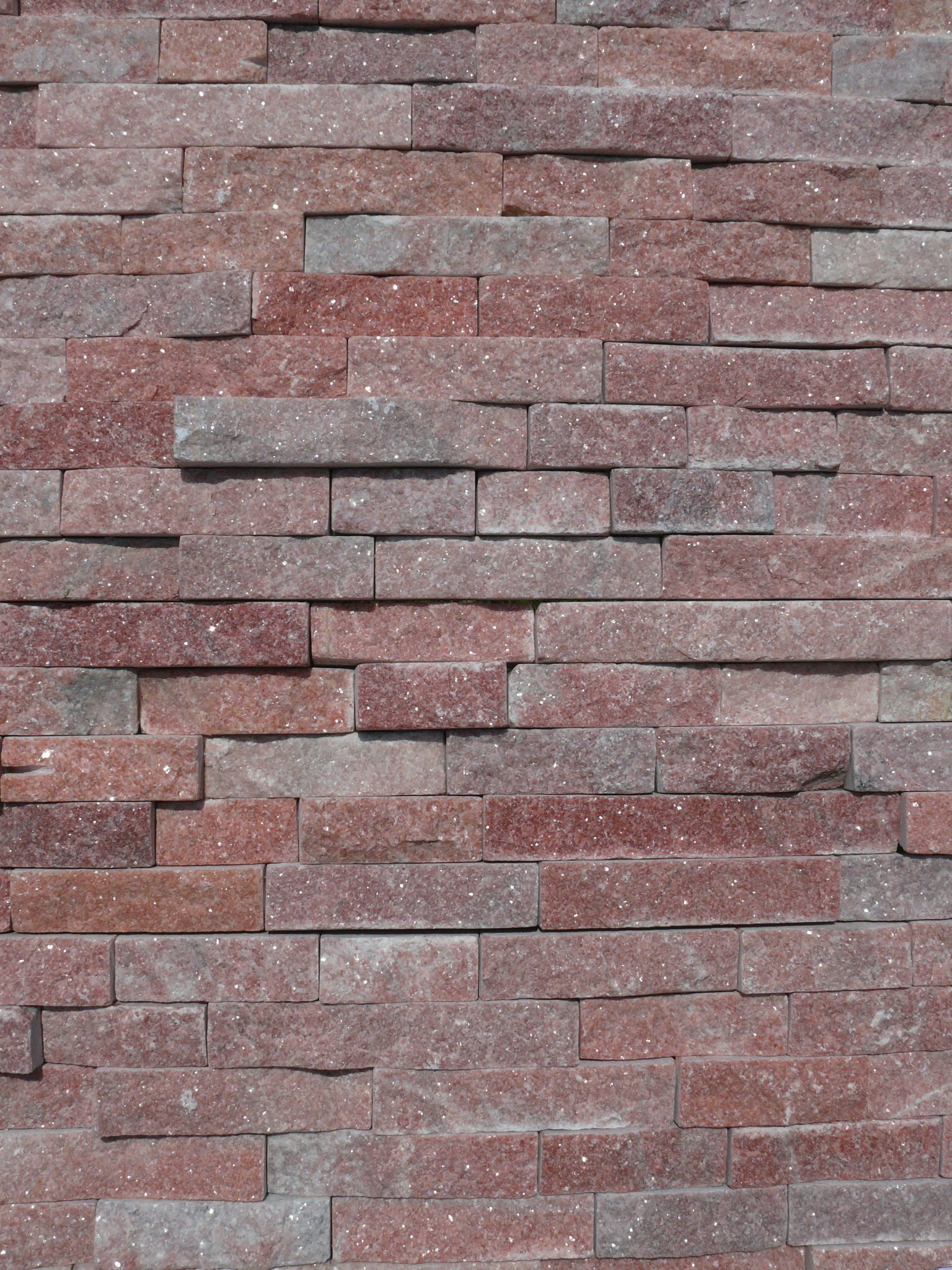 Red and gray stone veneer wall with staggered rectangular blocks.