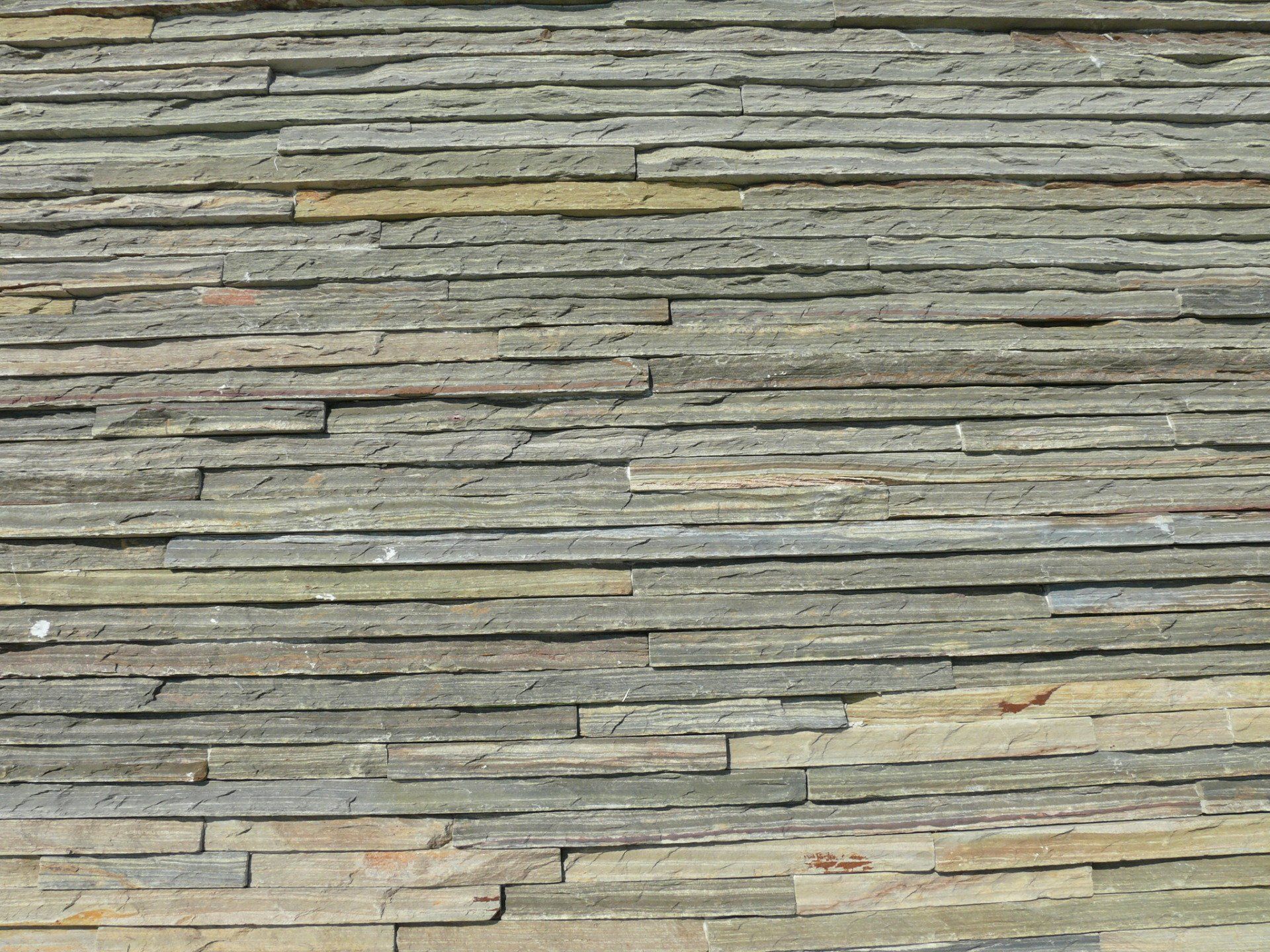 Horizontal rectangular stone wall, varying shades of gray and beige.