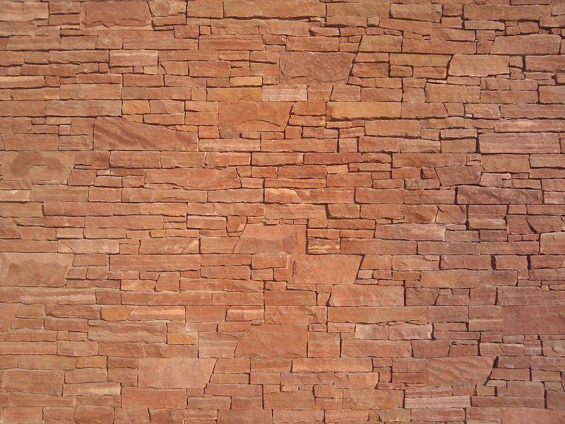 Reddish-brown stacked stone wall, with varying lengths and textures.