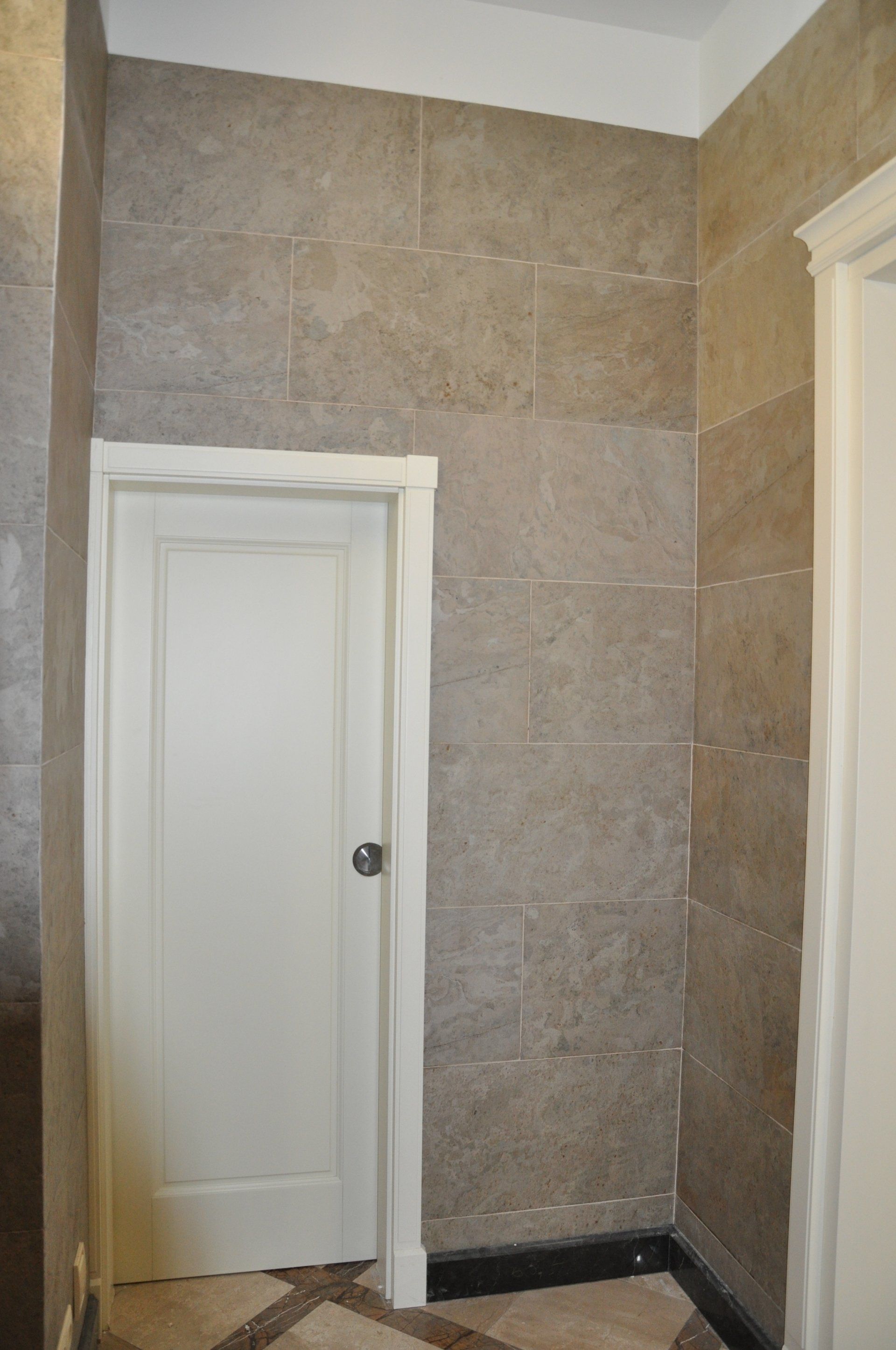 Room with gray tiled walls, white doors, and decorative flooring.