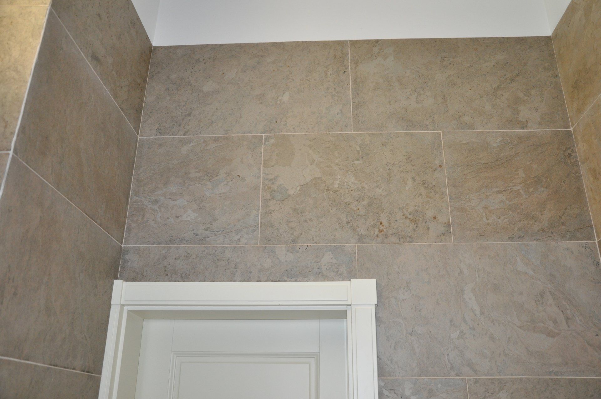 Beige tiled wall with white door frame.