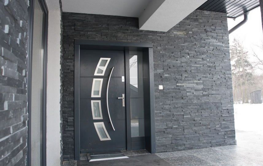 Dark gray front door with glass panels and stone facade.