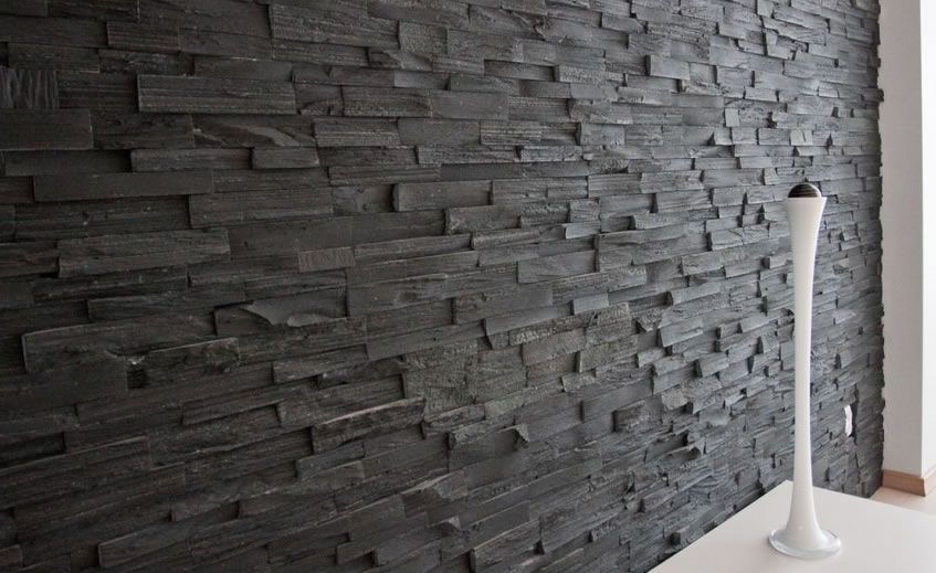 Black stacked stone wall with a white decorative vase.