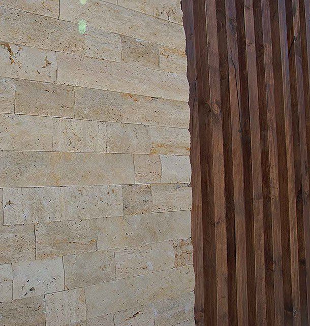 Beige brick wall juxtaposed with vertical dark wood slats.
