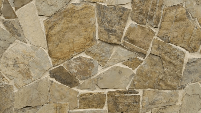 Stone wall with tan, brown, and grey irregularly shaped stones, with light mortar between them.