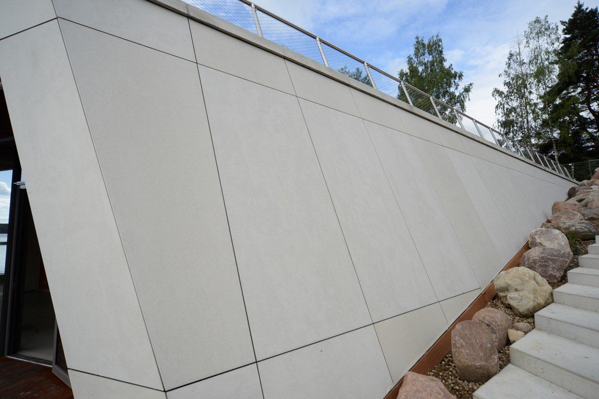 Modern building with angled, light-colored facade. Diagonal lines, rocks, and a stairway are visible.